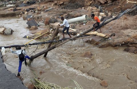 People walk across a makeshift bridge after a bridge was swept away in Ntozuma, South Africa, on April 12.